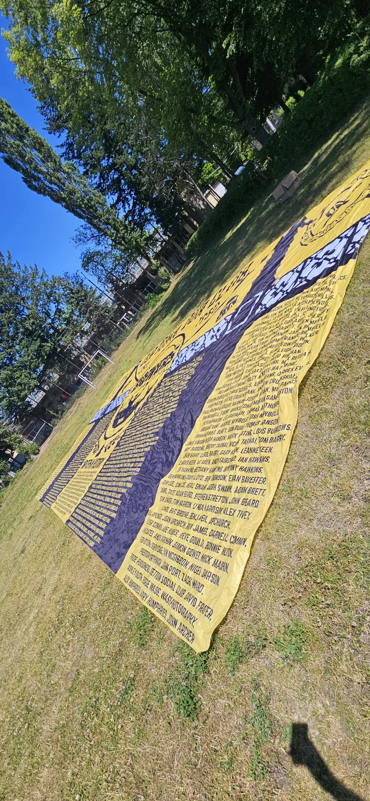 Yellow memorial sector flag with hundreds of names on the grass