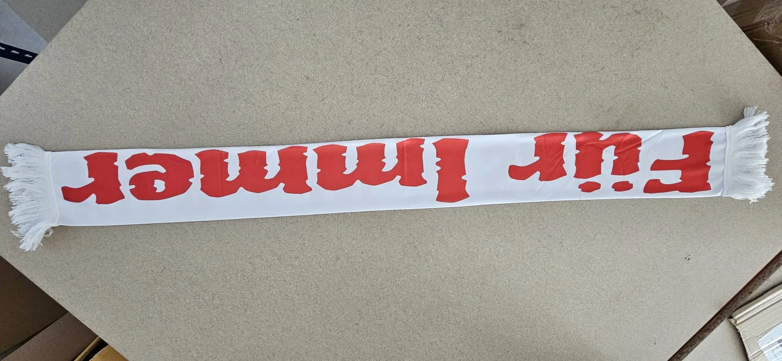 White scarf with red lettering Für immer and white tassels